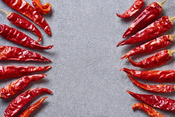 Top view of dried red chili peppers arranged on grey tabletop — Stock Photo