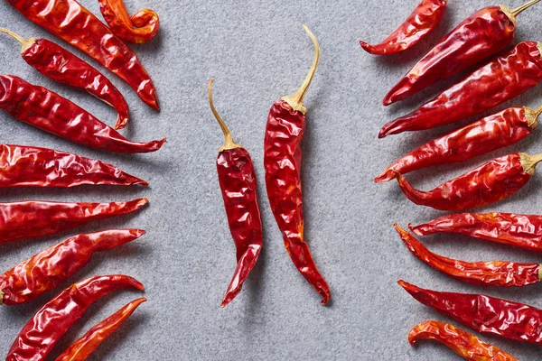 Top view of red chili peppers arranged on grey tabletop — Stock Photo