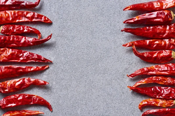 Top view of dried red chili peppers arranged on grey tabletop — Stock Photo