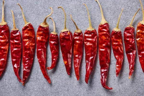 Vista superior de los chiles rojos dispuestos en la mesa gris - foto de stock