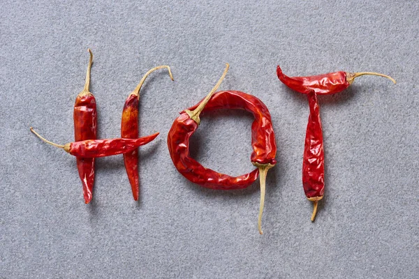 Vue du dessus des piments disposés en lettres chaudes sur la table grise — Photo de stock