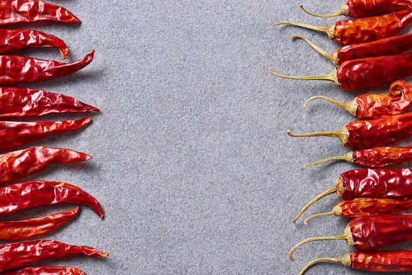 Top view of red chili peppers arranged on grey tabletop — Stock Photo