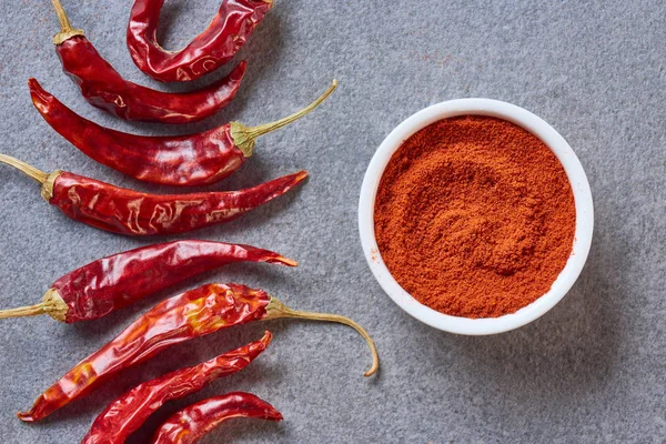 Draufsicht auf arrangierte gemahlene und gesunde Chilischoten auf grauer Tischplatte — Stockfoto