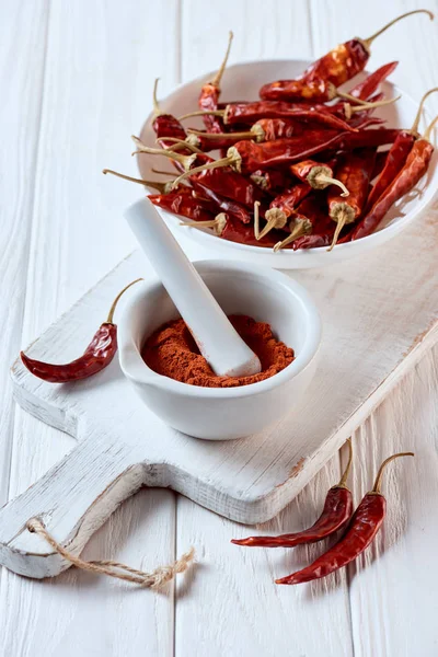 Close up view of grinded chili pepper in mortar with pestle on white wooden surface — Stock Photo