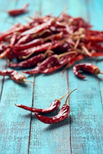 Close up view of dried chili peppers on blue wooden surface — Stock Photo