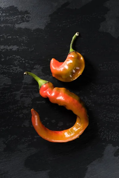 Top view of two chili peppers on black surface — Stock Photo