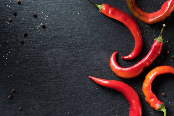 Elevated view of red organic chili peppers on black surface — Stock Photo
