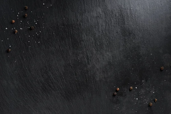 Top view of scattered peppers and salt on dark tabletop — Stock Photo