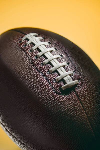 Primer plano de pelota de fútbol americano marrón aislado en amarillo - foto de stock