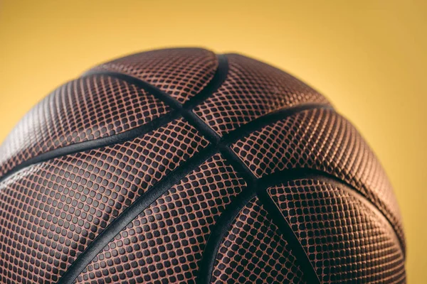 Primer plano de pelota de baloncesto marrón aislado en amarillo - foto de stock