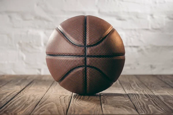 Brown leather basketball ball on wooden floor — Stock Photo