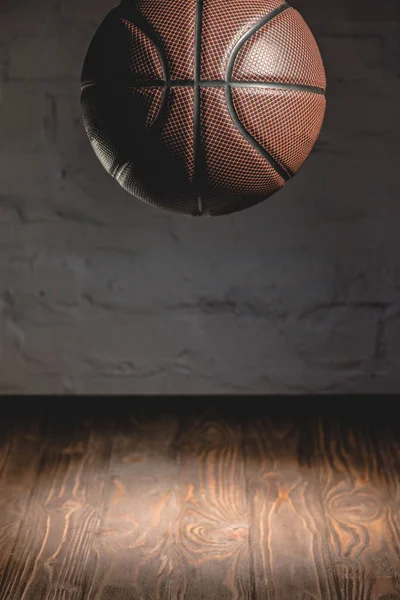 Brown basketball ball falling on wooden floor — Stock Photo
