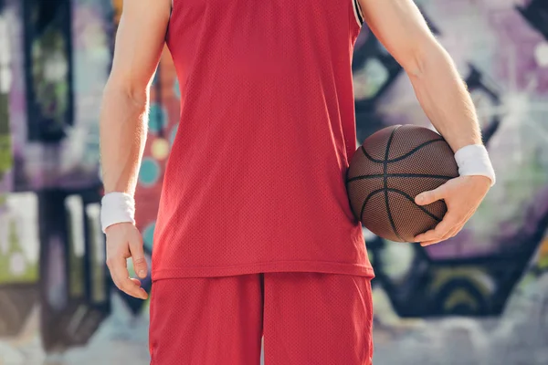 Обрезанное изображение баскетболиста, стоящего с баскетбольным мячом на улице — стоковое фото