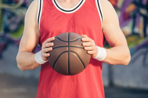 Cropped image of basketball player holding basketball ball on street — Stock Photo