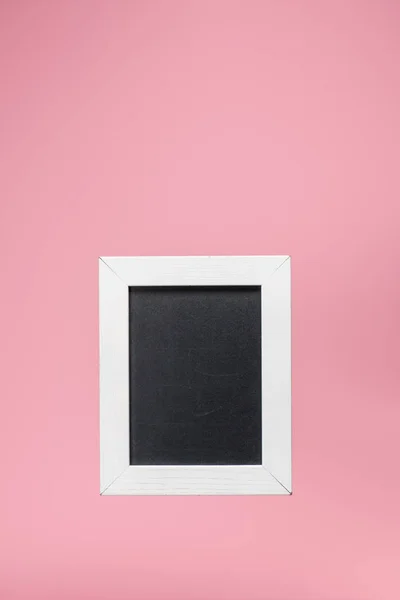 Una pizarra en marco blanco aislado en rosa - foto de stock