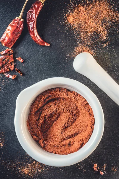 Vue de dessus de la poudre de chili aromatique et des piments rouges sur noir — Photo de stock