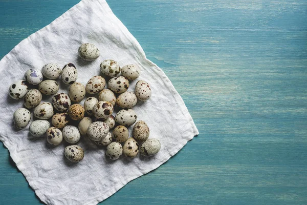 Fresh organic quail eggs on white cloth on turquoise wooden table — Stock Photo