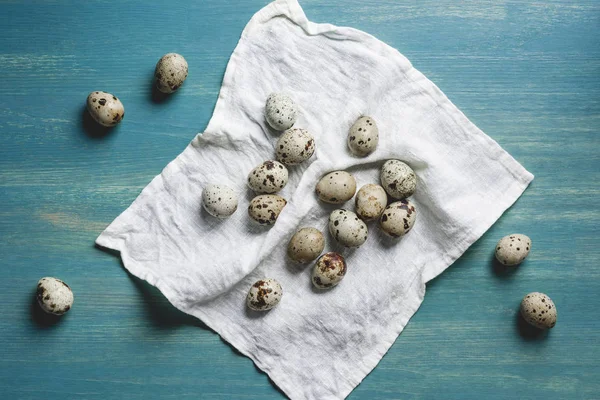 Top view of fresh organic quail eggs on white cloth on turquoise wooden table — Stock Photo