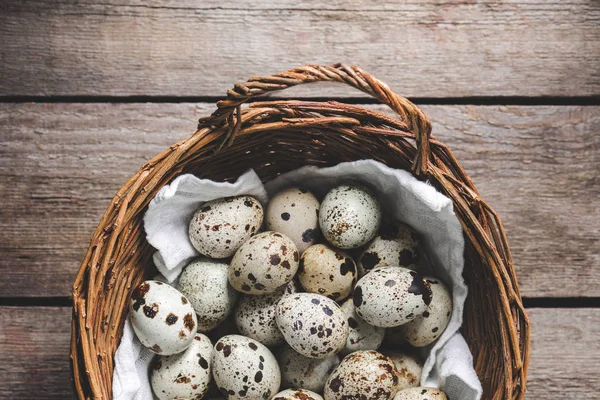 Top view of quail eggs in wicker basket on rustic wooden table — Stock Photo