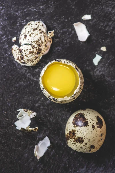 Top view of fresh raw broken quail egg with yolk on black — Stock Photo