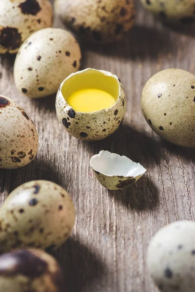 Vista ravvicinata di uova rotte e uova di quaglia sgusciate sul tavolo di legno — Foto stock