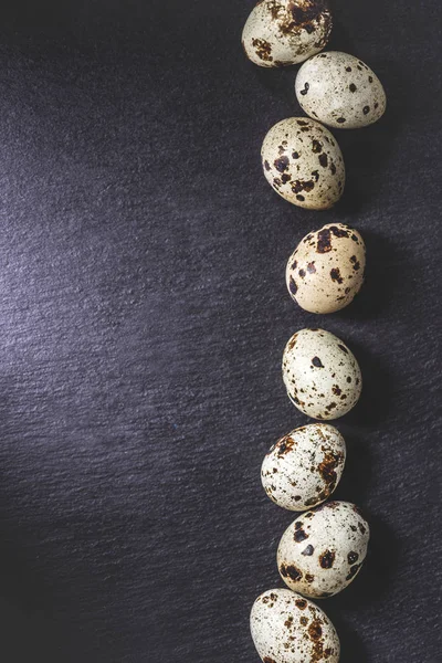 Vista superior de ovos de codorna saudáveis orgânicos crus em fundo preto — Fotografia de Stock