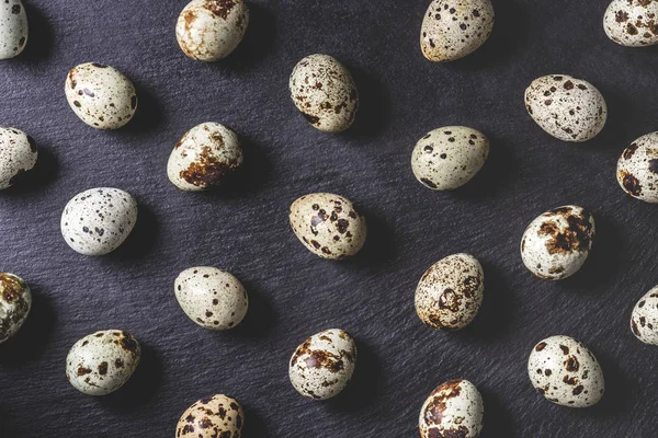 Top view of organic unshelled quail eggs on black background, seamless pattern — Stock Photo