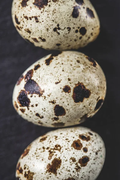 Вид зверху на органічні неушкоджені перепелині яйця на чорному, крупним планом — стокове фото