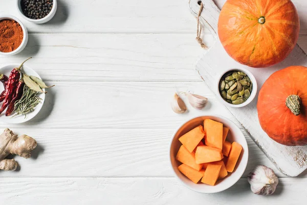 Vista superior de especias, calabazas, ajo y tabla de cortar en la mesa - foto de stock