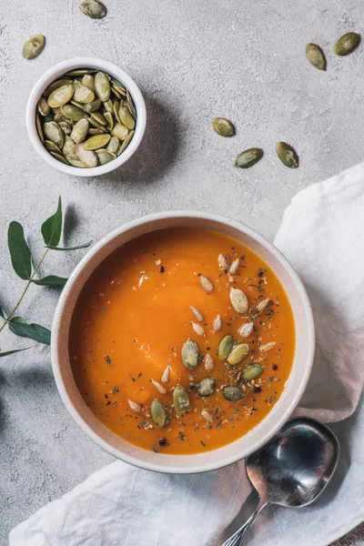 Top view of bowl with pumpkin soup and seeds on table — Stock Photo