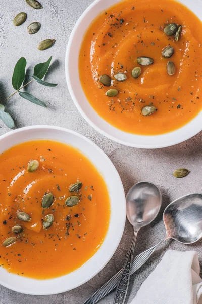 Top view of plates with pumpkin cream soup with seeds on table — Stock Photo