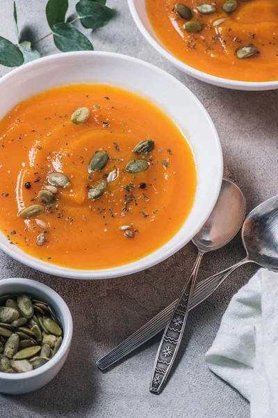 Close up view of plates with pumpkin cream soup with seeds on table — Stock Photo