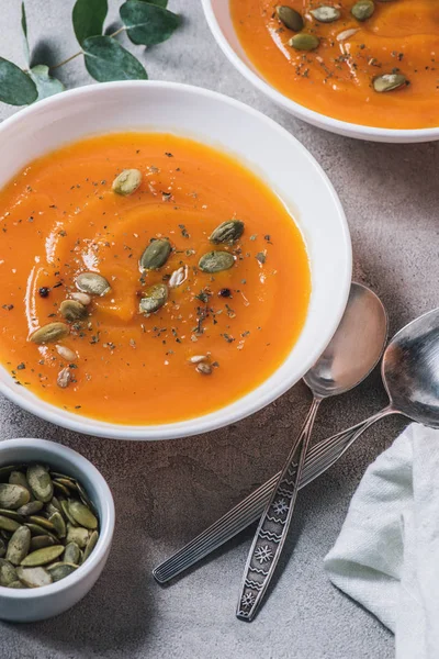 Cerrar la vista de los platos con sopa de crema de calabaza con semillas en la mesa - foto de stock