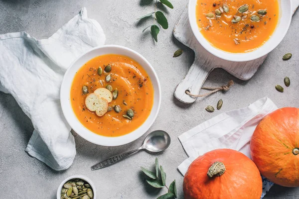 Vista superior de calabazas, platos con sopa de crema de calabaza rusks en la mesa - foto de stock