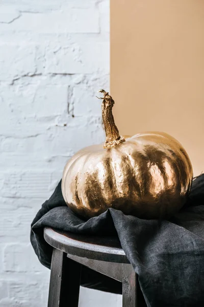 Close-up shot of halloween pumpkin painted in golden metallic in front of white brick wall — Stock Photo