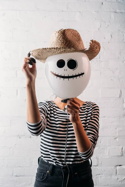 Woman holding halloween balloon with straw hat in front of head — Stock Photo