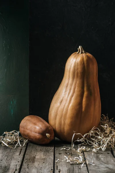 Close up view of ripe pumpkins on wooden surface on dark background — Stock Photo