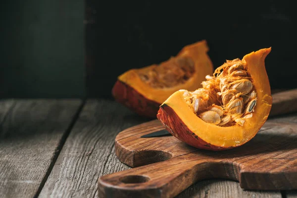 Vue rapprochée des moitiés de citrouille crues sur planche à découper sur plateau en bois — Photo de stock