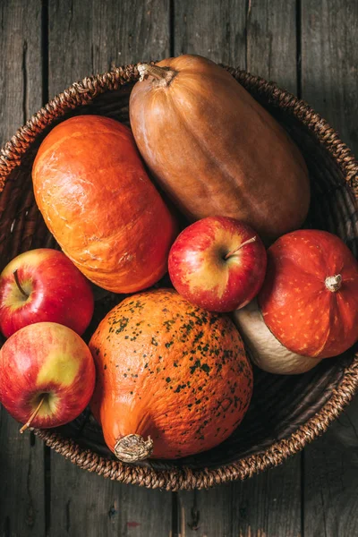 Vista superior de manzanas maduras y calabazas cosecha otoño en cesta sobre fondo de madera - foto de stock