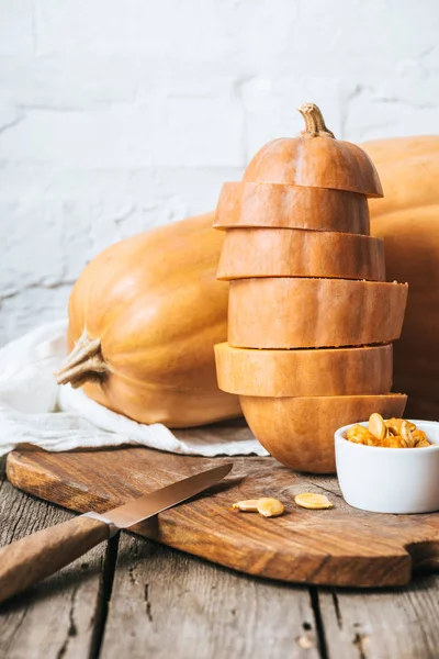 Close up view of arranged pumpkins and knife on wooden surface and white brick wall background — Stock Photo