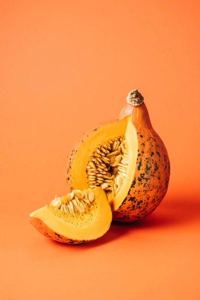 Vista de cerca de calabaza cruda cortada sobre fondo naranja - foto de stock