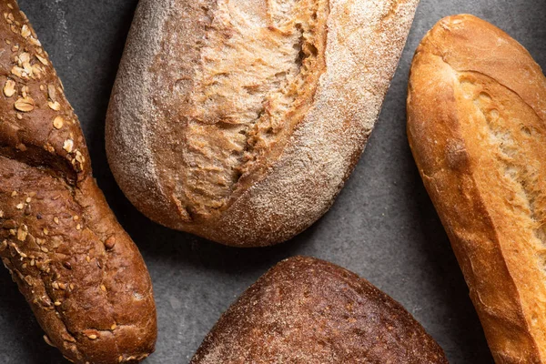 Flat lay with loafs of baked bread on grey tabletop — Stock Photo