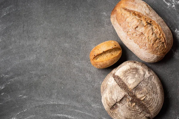 Deitado plano com loafs de pão assado em mesa cinza — Fotografia de Stock