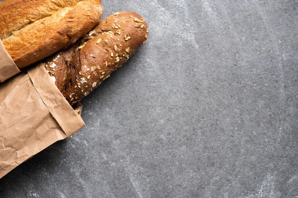 Top view of baguettes in paper bag on grey surface — Stock Photo