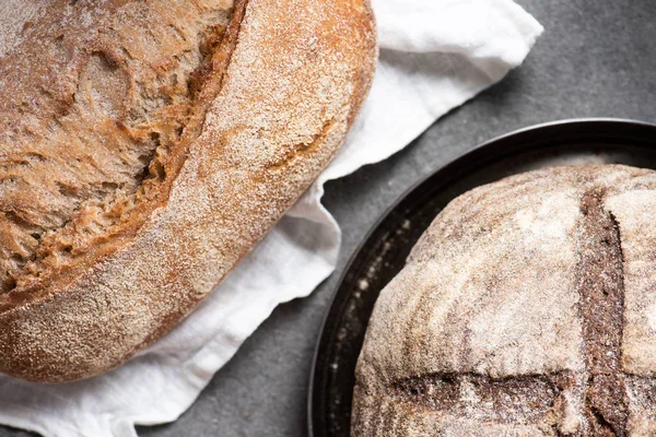 Vista superior de loafs no pão assado em linho e placa na superfície cinzenta — Fotografia de Stock