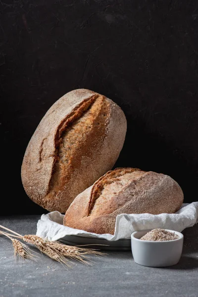 Close up view of loafs of ciabatta and wheat on black background — Stock Photo