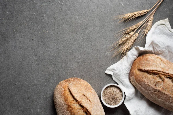 Flat lay with arranged bread and wheat on grey tabletop — Stock Photo