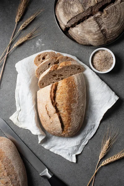 Flat lay with arranged bread, knife and wheat on grey tabletop — Stock Photo