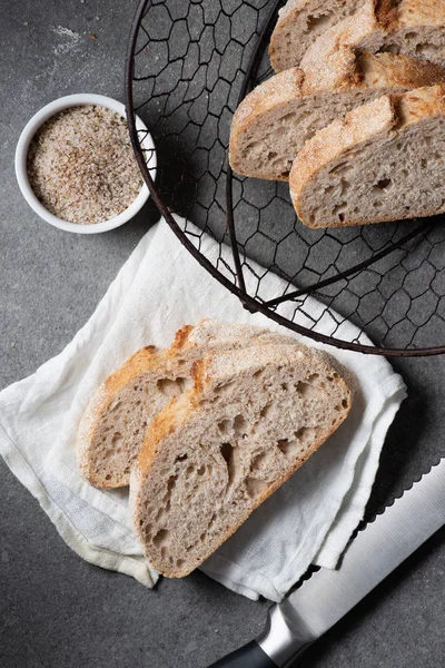 Flat lay with cut loaf of bread, knife and white linen on grey tabletop — Stock Photo