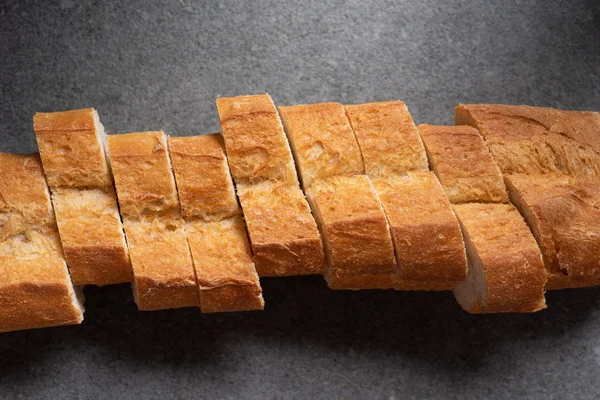 Top view of cut baguette on grey surface — Stock Photo
